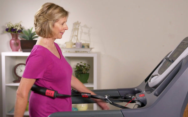 Senior woman walking on a treadmill while using Treadmill Max treadmill stability belt