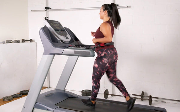 Woman jogging on a treadmill while using Treadmill Max treadmill stability belt