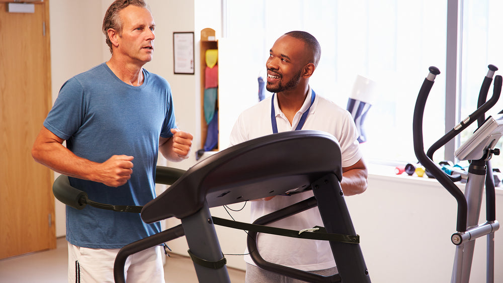 Health professional smiles as he watches a client use a treadmill while wearing Treadmill Max treadmill stability belt