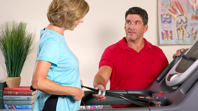 Health professional assists senior woman walking on a treadmill while using Treadmill Max treadmill stability belt
